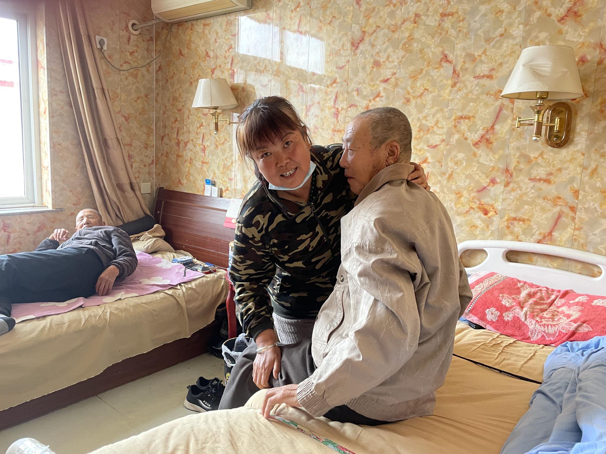 李仲娥在把一個老人抱到床上，老人該午睡了。新京報記者 趙利新 攝