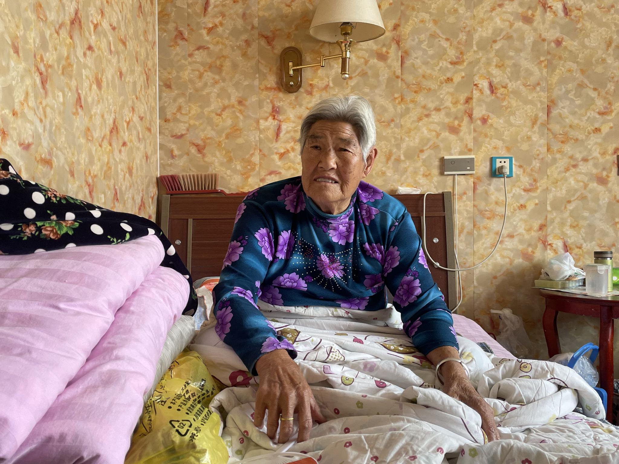 80歲的王桂芝腿腳不便，沒有去院里曬太陽，坐在床上休息。新京報記者 趙利新 攝