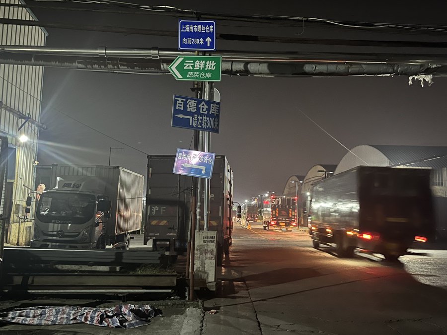 物流园区内分布着多家企业，路边也停靠着不少货车。