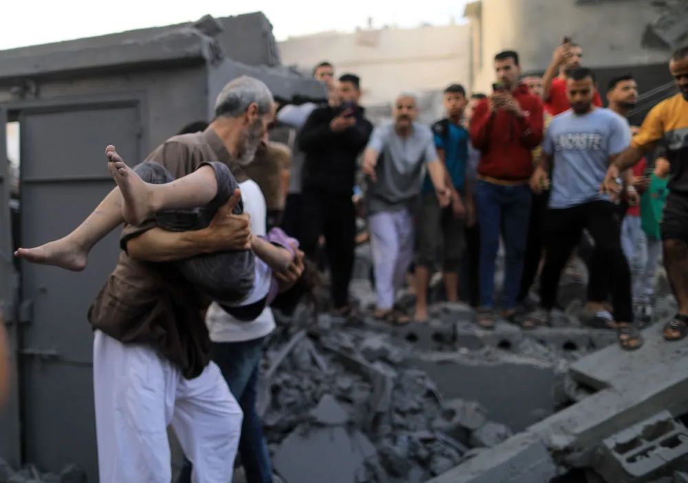 10月14日，在加沙地帶南部城市汗尤尼斯，人們在遭以色列空襲炸燬的建築中救援。新華社發（亞西爾·庫迪攝）