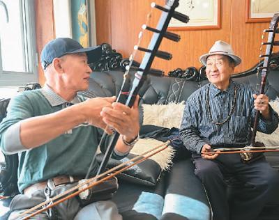 明安宝(右)在家中与乐队成员交流。新华社记者 贝 赫摄