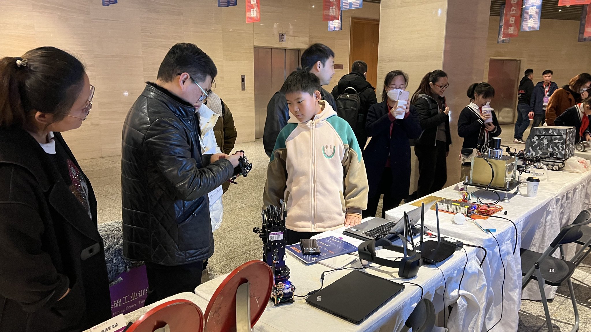 11月18日,在清華大學基礎工業訓練中心的展位前,參加活動的青少年認真聆聽產品講解。新京報記者 李聰 攝