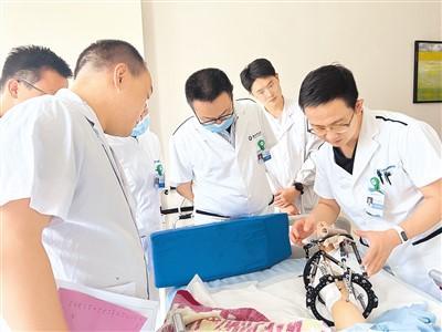 图为杜辉(右一)在贵州医院为当地医生讲解诊疗技术。北京积水潭医院供图