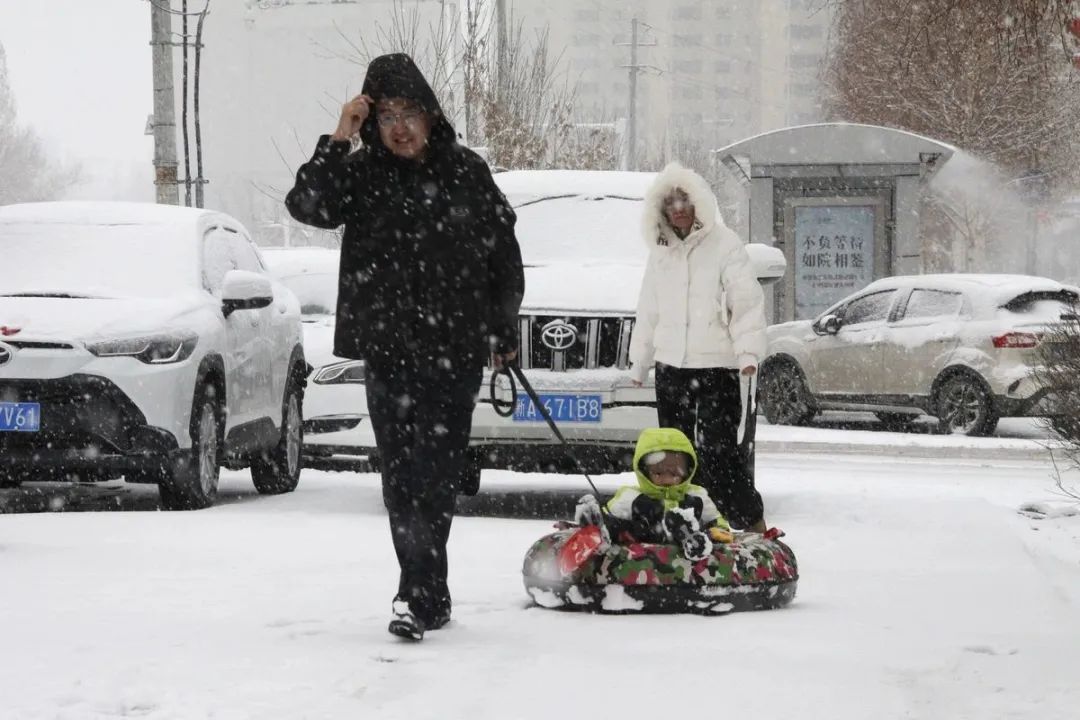 11月25日,新疆阿勒泰,父母带孩子在街道上滑雪圈。