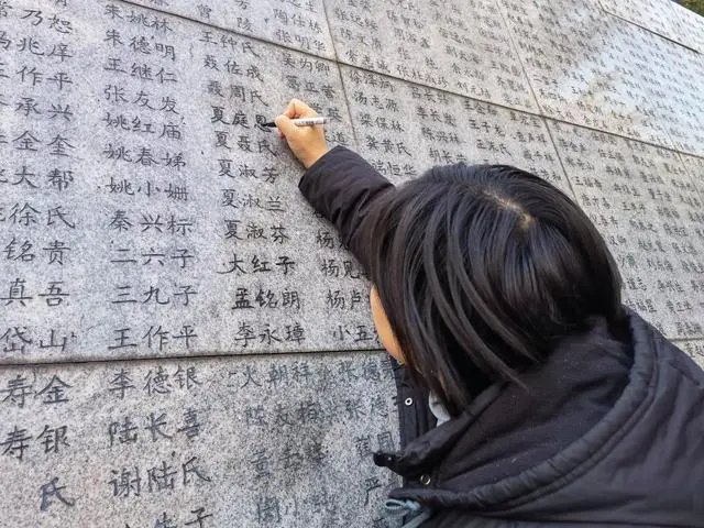 南京大屠殺倖存者夏淑琴的外孫女夏媛為「哭牆」上家人的姓名「描新」。 新華社記者 邱冰清 攝
