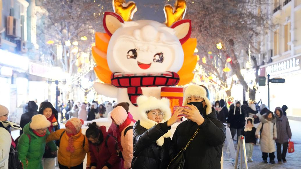 1月11日,游客在哈尔滨中央大街的雪雕前自拍。 新华社记者 王建威 摄