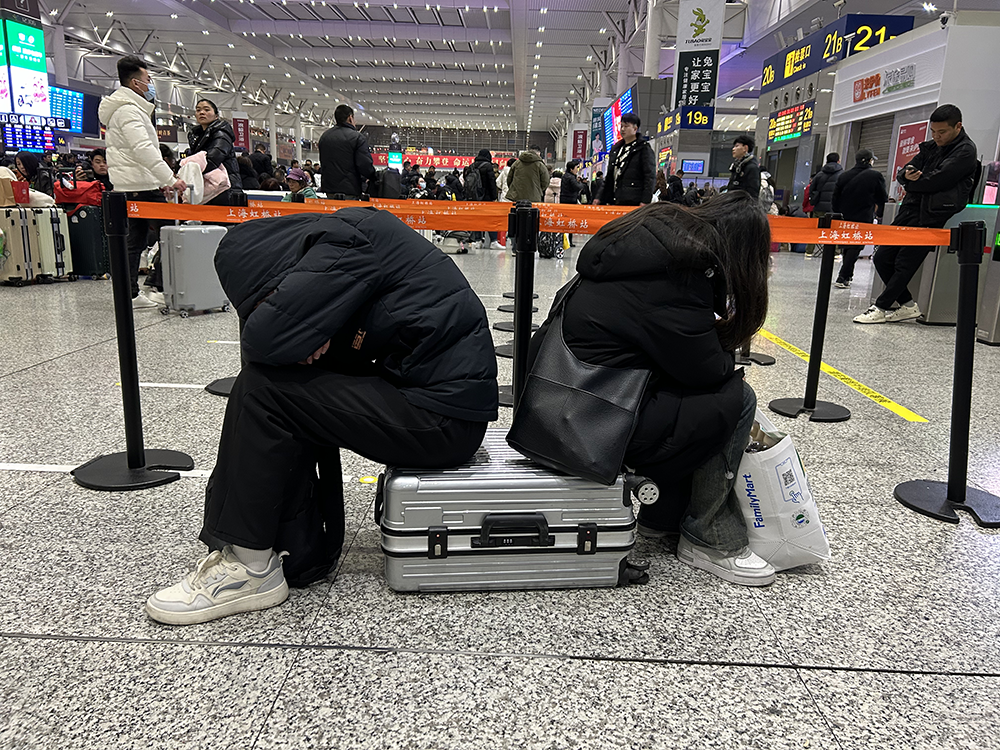 2月4日凌晨2时,上海虹桥火车站候车大厅,候车旅客坐在行李箱上休憩。