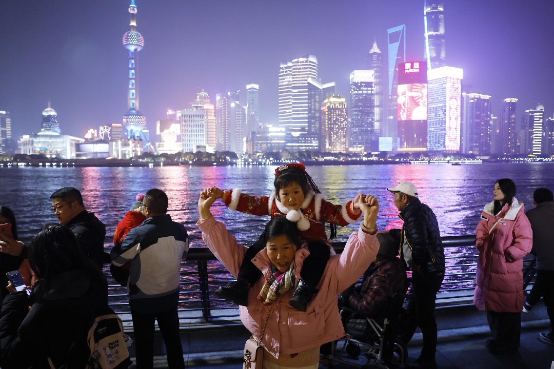 2024年2月9日,上海,游客带着孩子在外滩滨江步道上欣赏黄浦江两岸美景。中新社记者 殷立勤 图