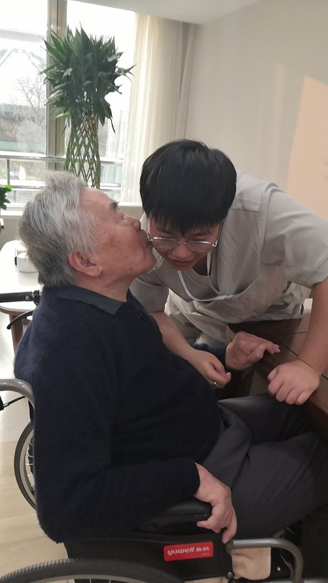     護理員王九達為一位老人服務後，老人在他臉上親了一口，表示感謝。受訪者供圖