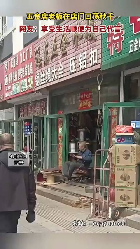 五金店老板在自家店门口荡秋千