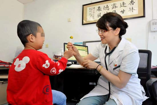     吳潤暉醫生在診室里遞給血友病患兒糖果。受訪者供圖