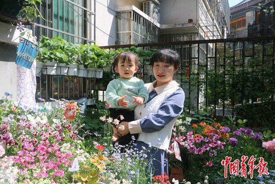     馮興抱著兩歲的女兒在陽台賞花。中青報·中青網記者 王海涵/攝
