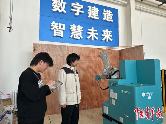     內蒙古建築職業技術學院智能建造技術專業學生郭蒙（右一）演示操作噴塗機器人。中青報·中青網記者 石佳/攝