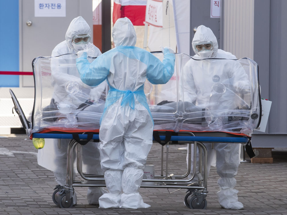 2020年3月11日，在南韓首爾，醫護人員將一名患者轉送至醫院。新華社發（李相浩攝）
