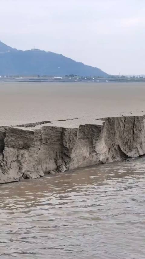 钱塘江北岸堆积了一两米高滩涂也开始随着，江水大片大片的坍塌…