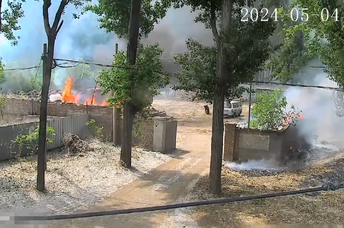 監控錄像中，男子點燃柳絮後，附近草地起火引燃木頭堆垛。圖源：通州區消防救援支隊