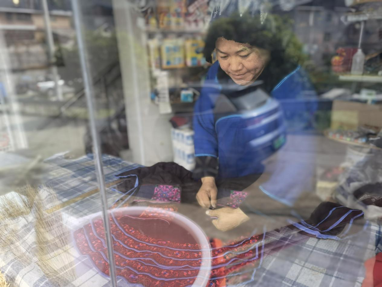 曹頂秀在自家商店的櫥窗後，製作楓香印染紡織品。受訪者供圖