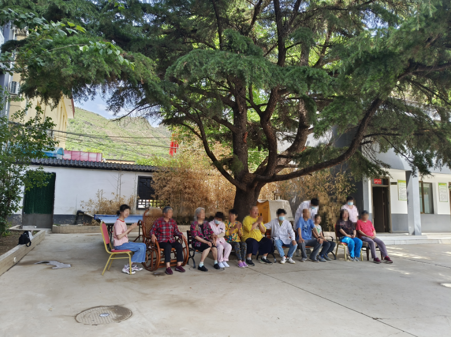 北京仙棲穀精神障礙托養中心內，學員們在大樹下乘涼，醫護人員在一旁照護。  新京報記者 葉紅梅 攝