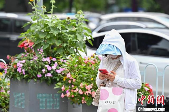 6月13日,廣東廣州,市民遮陽出行。當日,受高空槽和西南季風影響,廣州城區氣溫與濕度持續升高,悶熱天氣持續。 陳驥旻 攝