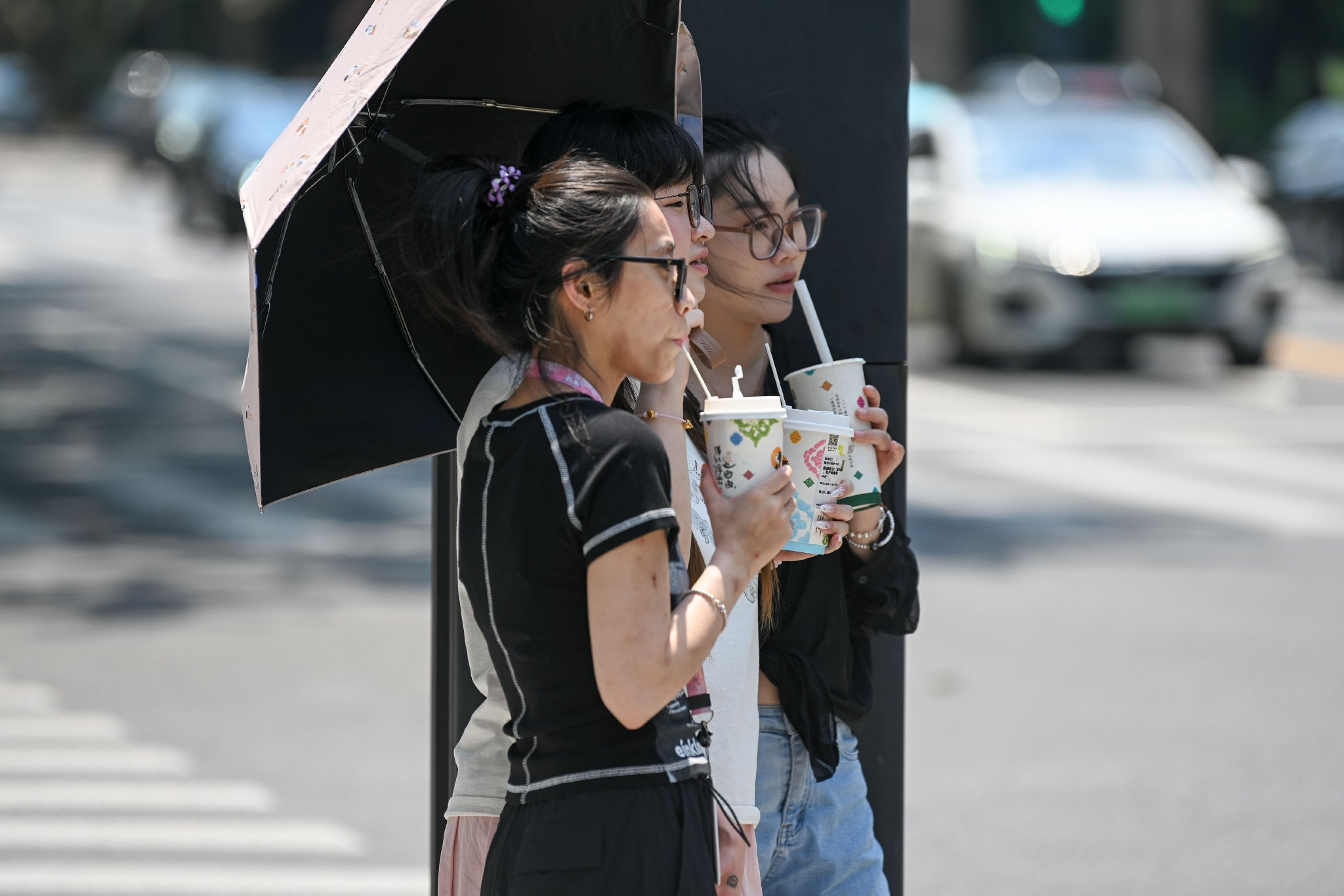 2024年7月4日,上海,市民撑着伞,站在柱子的阴影处等待绿灯通行。澎湃新闻记者 朱伟辉 图
