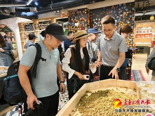 7月14日,在国际大巴扎,采访团记者正在了解新疆干果。记者唐红梅摄