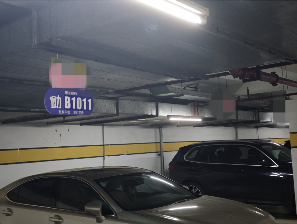 隽峰苑小区地下停车场车位上方挂着互助停车的车位号。