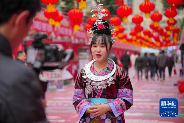 2月2日,一名身着民族服饰的姑娘在“村超村晚”年货大集市上视频推介当地农特产品。新华社发(龙建睿 摄)