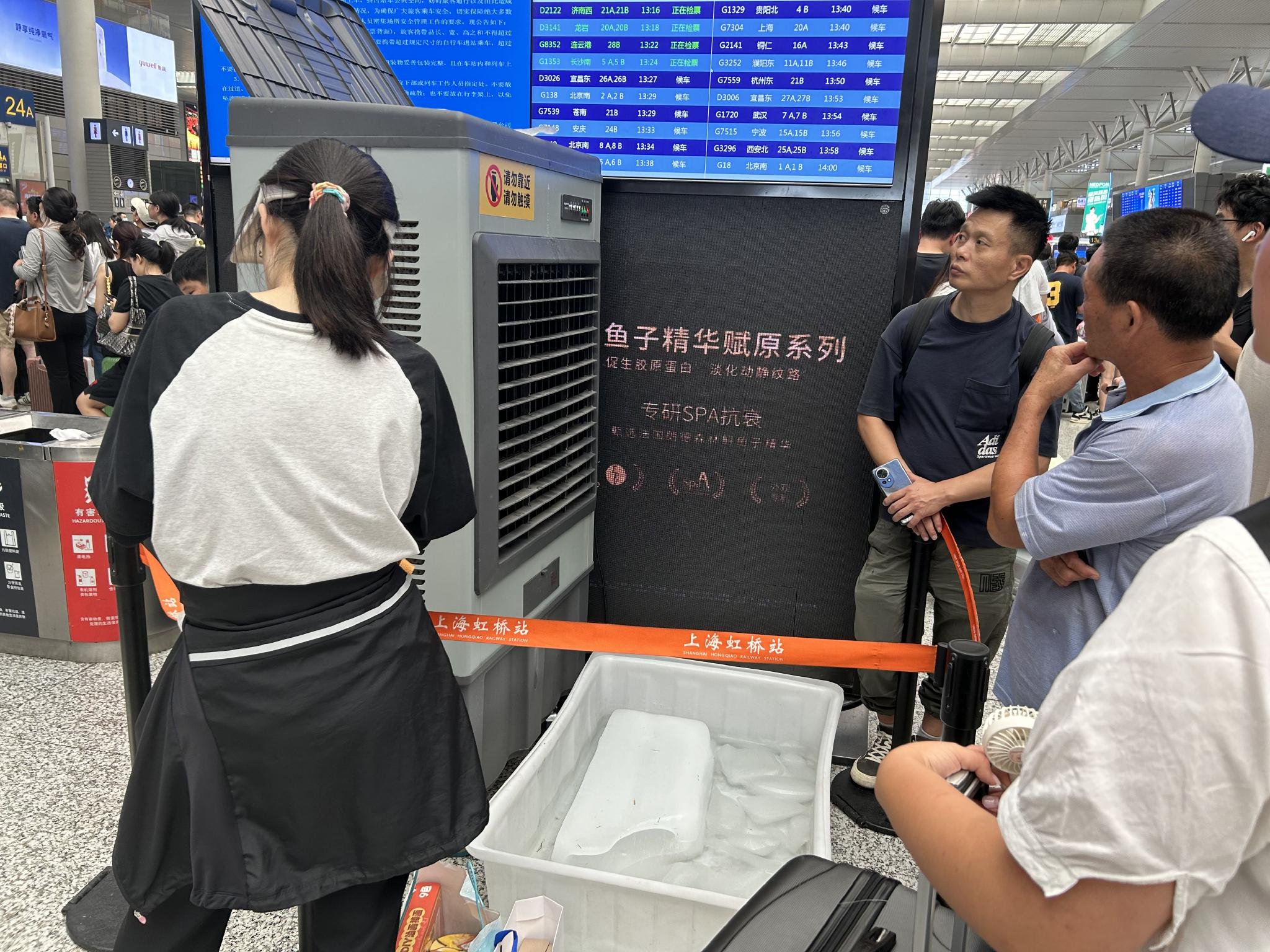 8月7日中午,上海虹桥火车站候车大厅,一些旅客站在冷风机出风口。