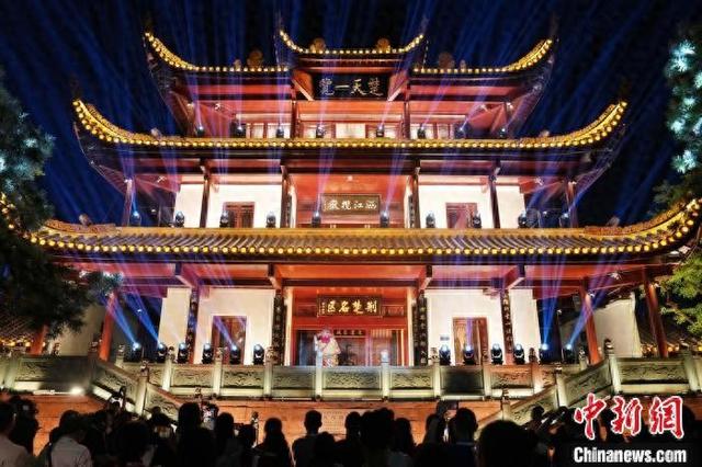 9月24日晚,长沙天心阁光影公园流光溢彩,天心阁主阁下,游客与“魁星”趣味互动。中新社记者 杨华峰 摄