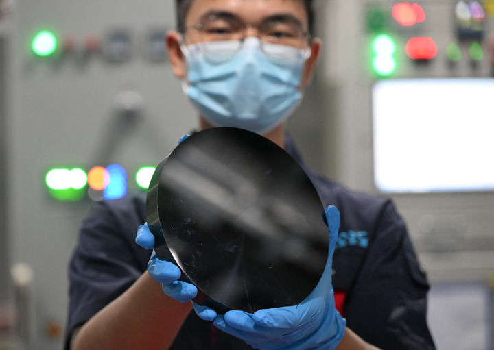 在鲁信集团中晶芯源半导体科技有限公司生产车间内,一位工作人员在展示8英寸碳化硅晶锭(8月13日摄)。新华社记者 李贺 摄