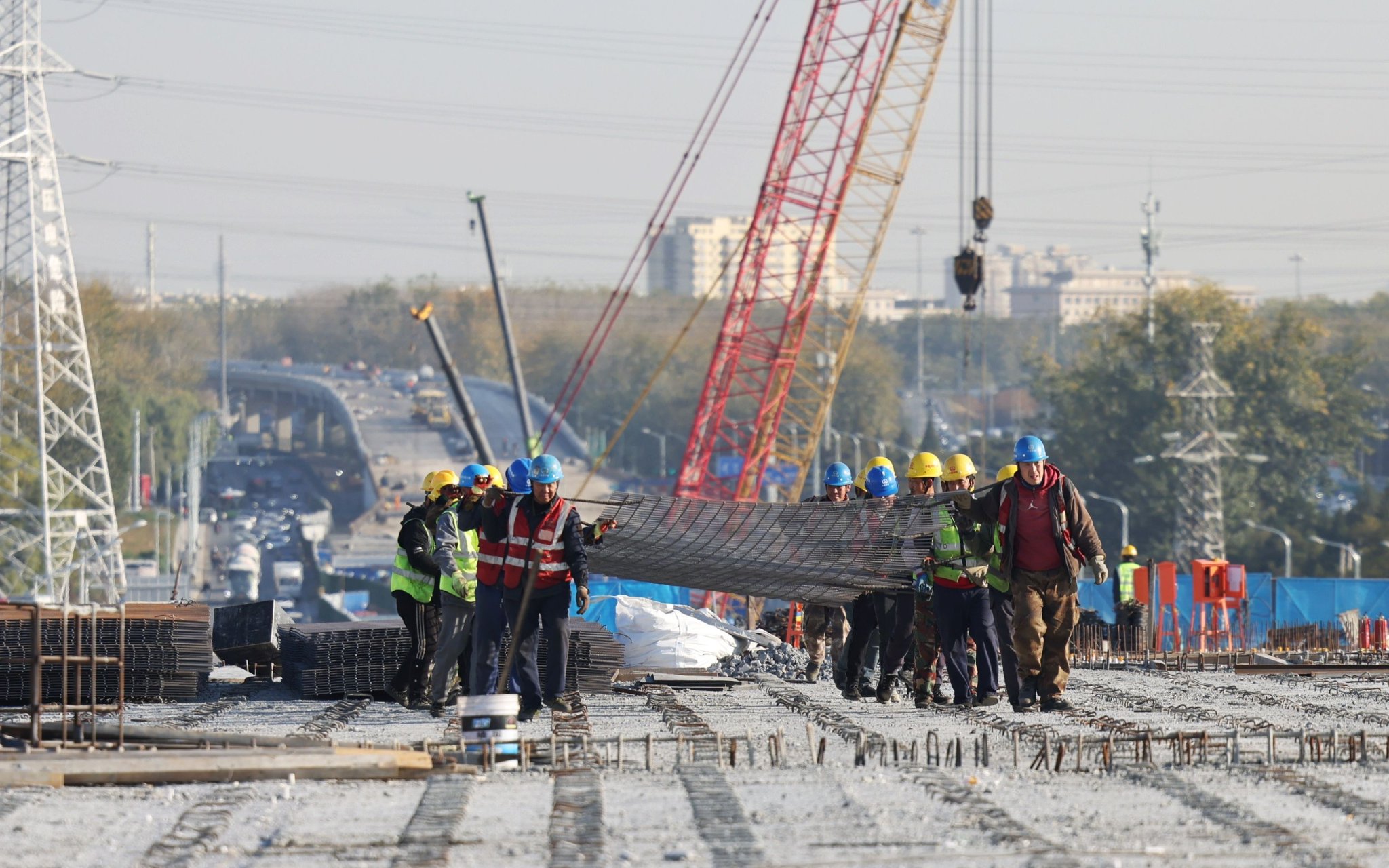 11月6日，京密路改造施工現場，工人們合力搬運建材。新京報記者 王貴彬 攝