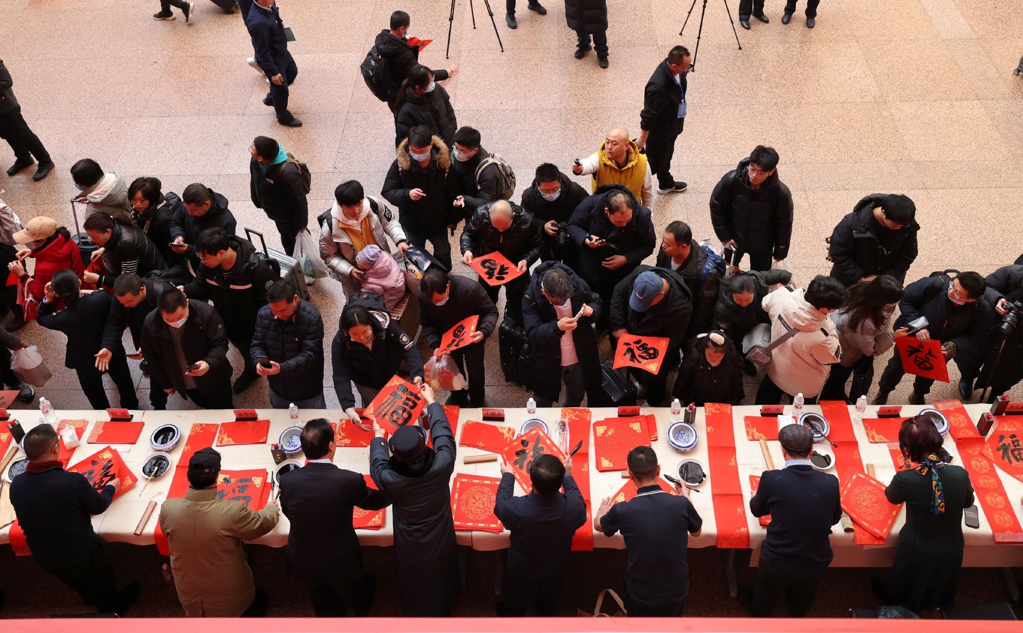 1月22日，書法家在北京西站書寫春聯福字送給旅客。新京報記者 王貴彬 攝