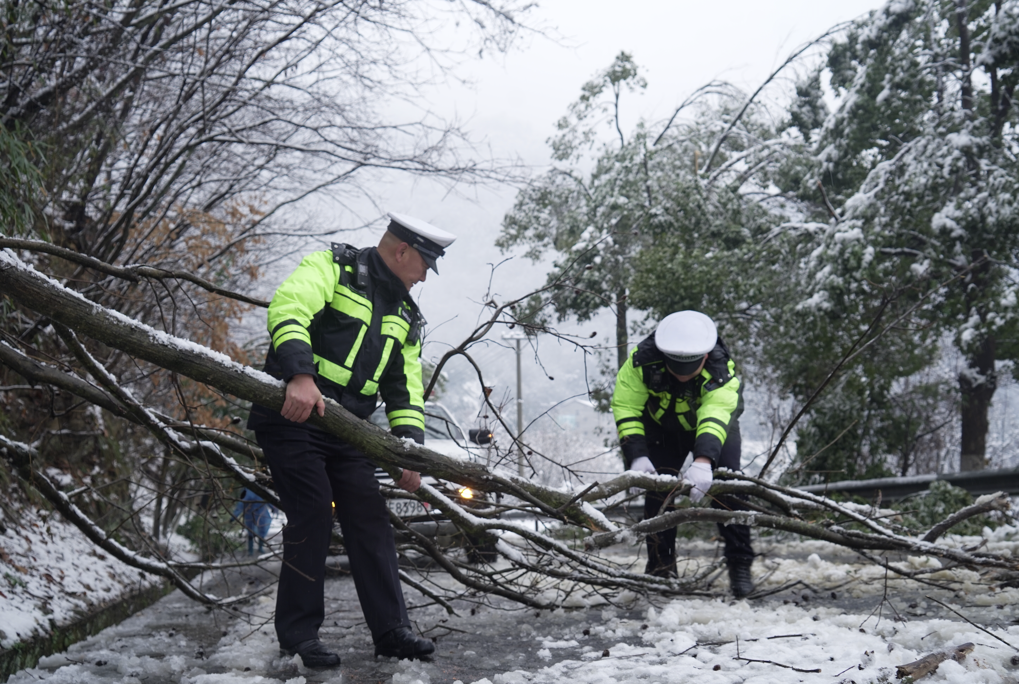 春節期間,湖北穀城縣突發降雪致使山區道路交通受阻,穀城縣公安局交警大隊二中隊民警在積雪路段開展路障清理作業。鄒靜宇 攝