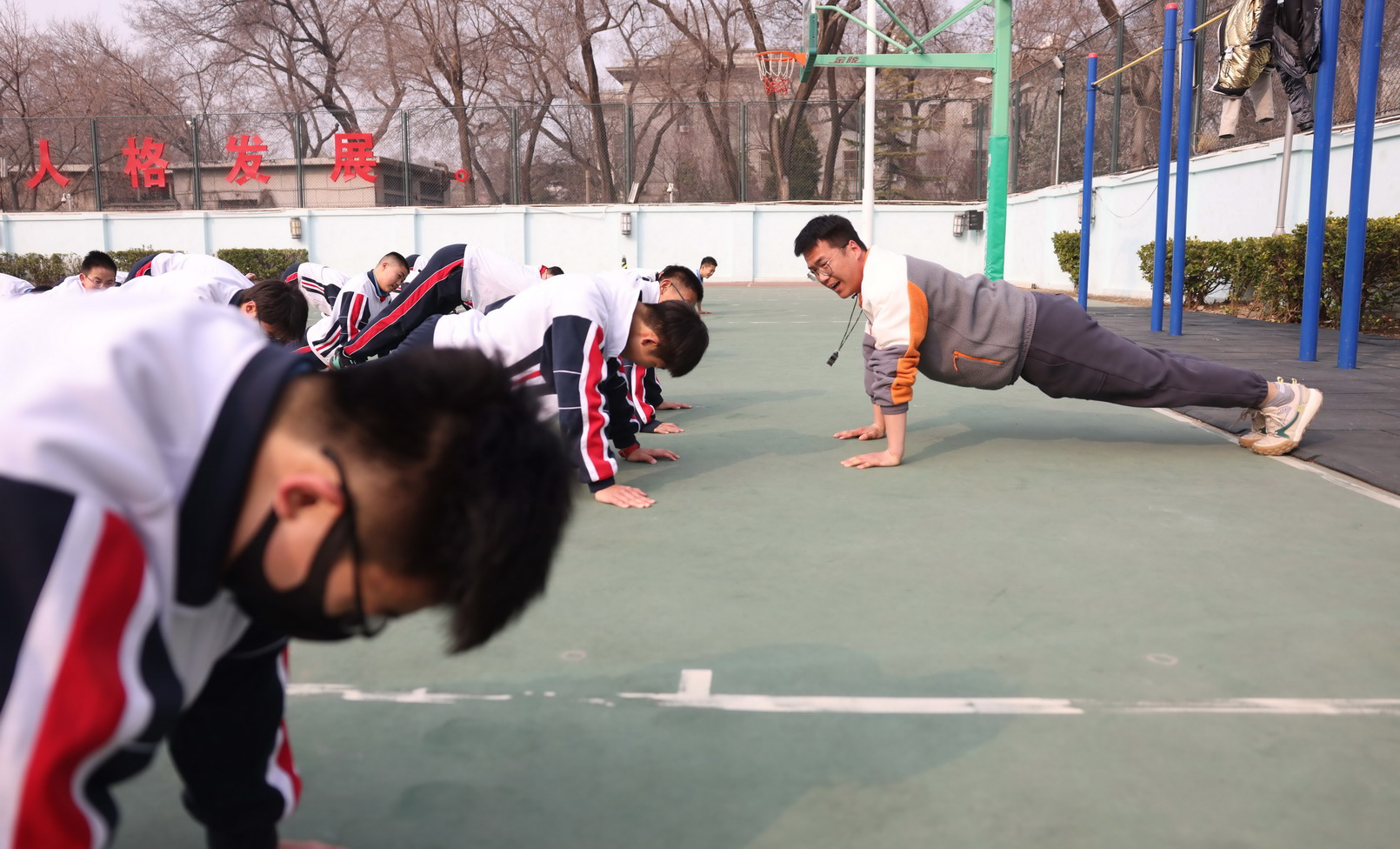 3月10日上午,東直門中學操場,體育教師崔佳峰和男生一起做俯臥撐。新京報記者 李木易 攝