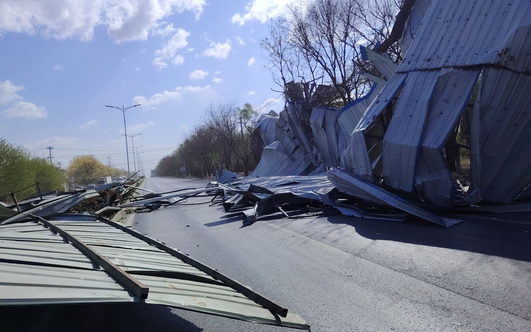 今早,公路養護人員巡查發現,房山一廠房彩鋼頂被風吹翻橫在路中,影響通行。北京市交通委房山公路分局供圖