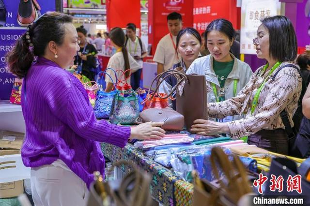 4月14日,海南海口,马来西亚企业展出的箱包吸引参观者。中新社记者 骆云飞 摄