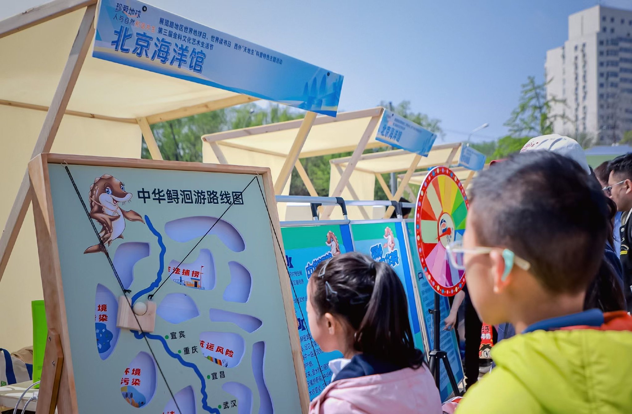 小朋友們在北京海洋館展台參觀中華鱘洄遊路線圖。新京報記者 薛珺 攝