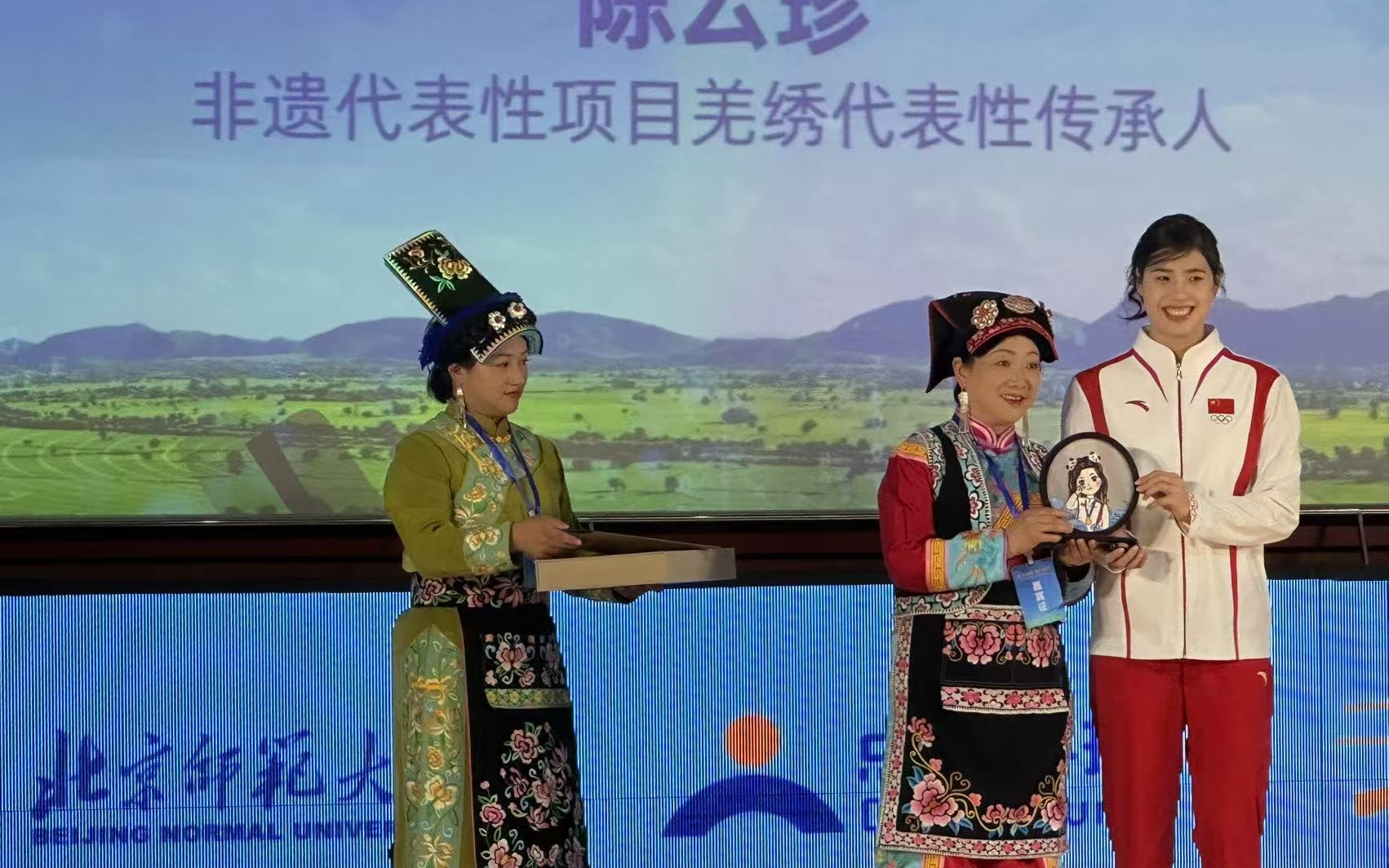 國家非遺代表性項目羌繡代表性傳承人、黨的二十大代表陳雲珍(中)給張雨霏送上親手做的羌繡。 新京報記者劉洋 攝