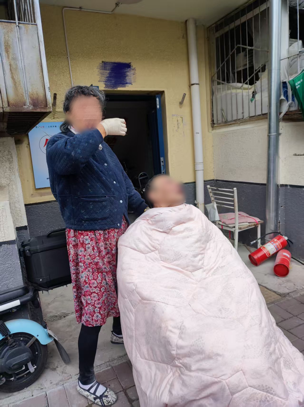 火滅後,司女士和輪椅上的老伴在單元樓門口。受訪者供圖