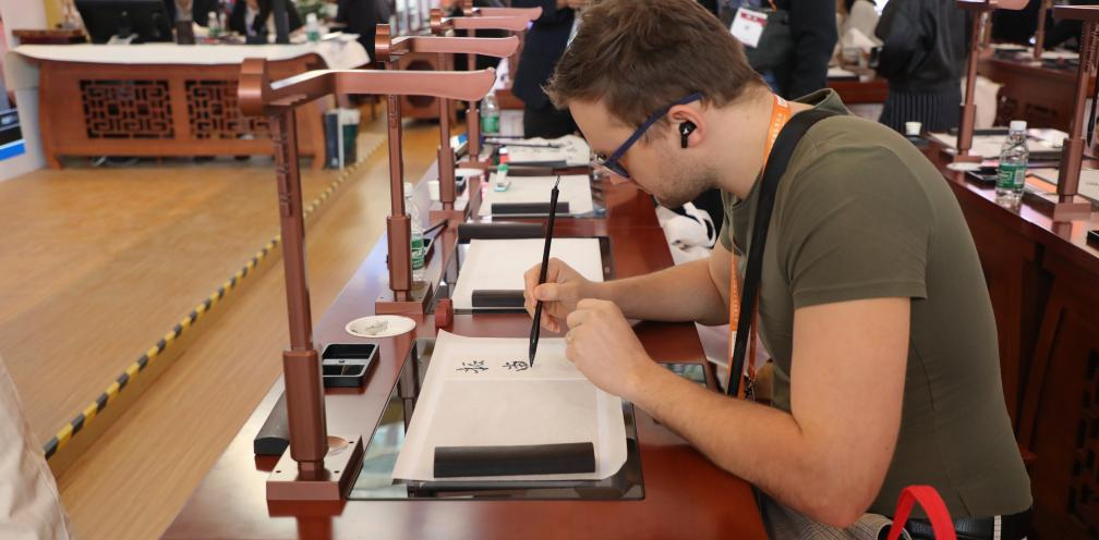 外国友人在第 85 届中国教育装备展示会上体验智慧书法。(全媒体记者杜瑞芳 摄)