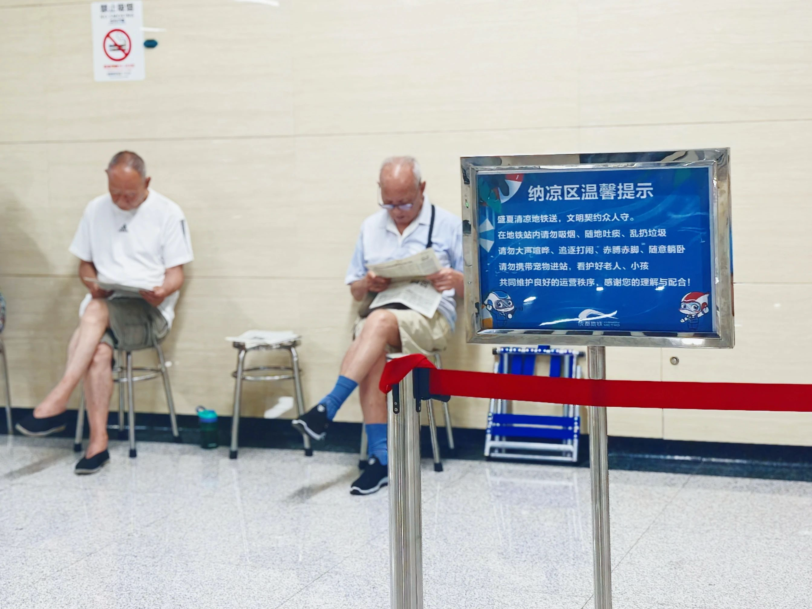 成都地鐵全線網423座車站均設納涼區,兩位老人正在看報。圖源:成都地鐵