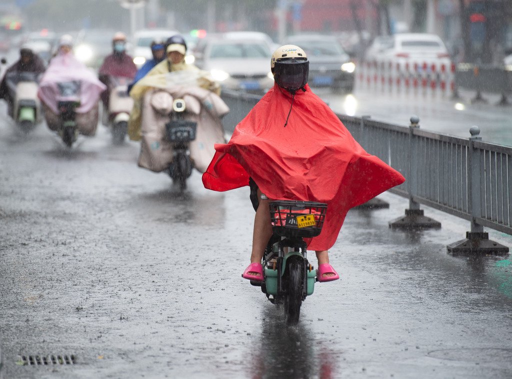 2025年6月20日,江苏省淮安市,市民冒雨在市区健康东路上出行。视觉中国 图