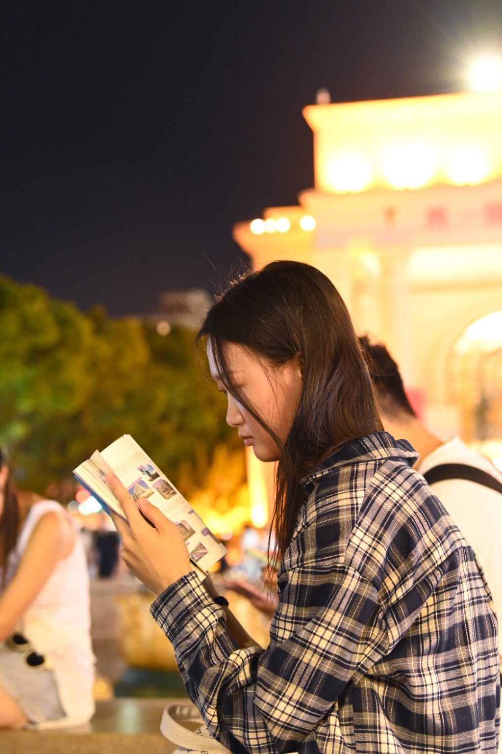 借着灯光,一位姑娘沉浸在刚买的书中。澎湃新闻记者 吴栋 图