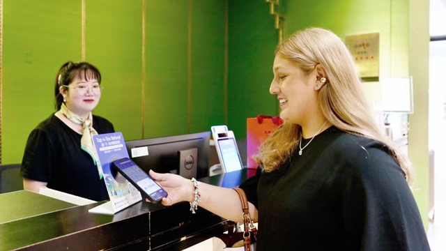 图为墨西哥游客在杭州万事利用“支付宝碰一下”2分钟完成退税。