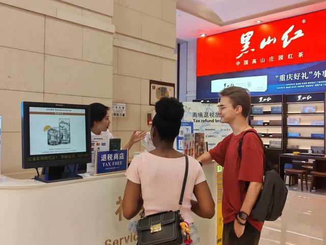图为在解放碑的重庆环球金融中心离境退税服务台,工作人员为来自俄罗斯和西非多哥的游客介绍离境退税“即买即退”服务。
