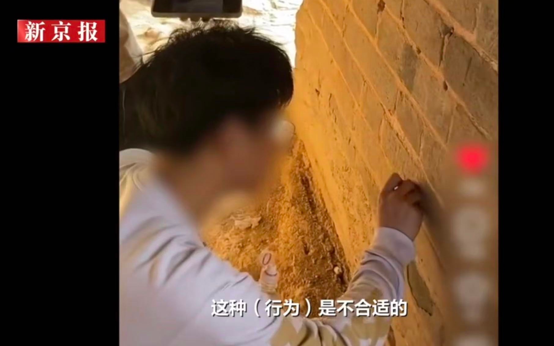 男子在長城上刻名字，目前已被密雲警方拘留。 新京報我們影片截圖