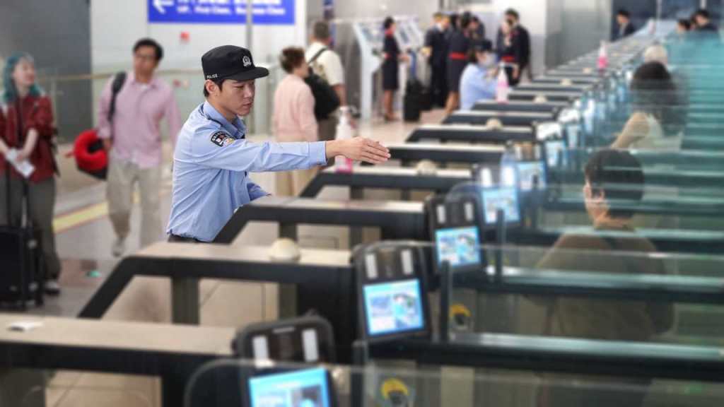 移民管理警察引导旅客使用快捷通道通关。李宇航 摄