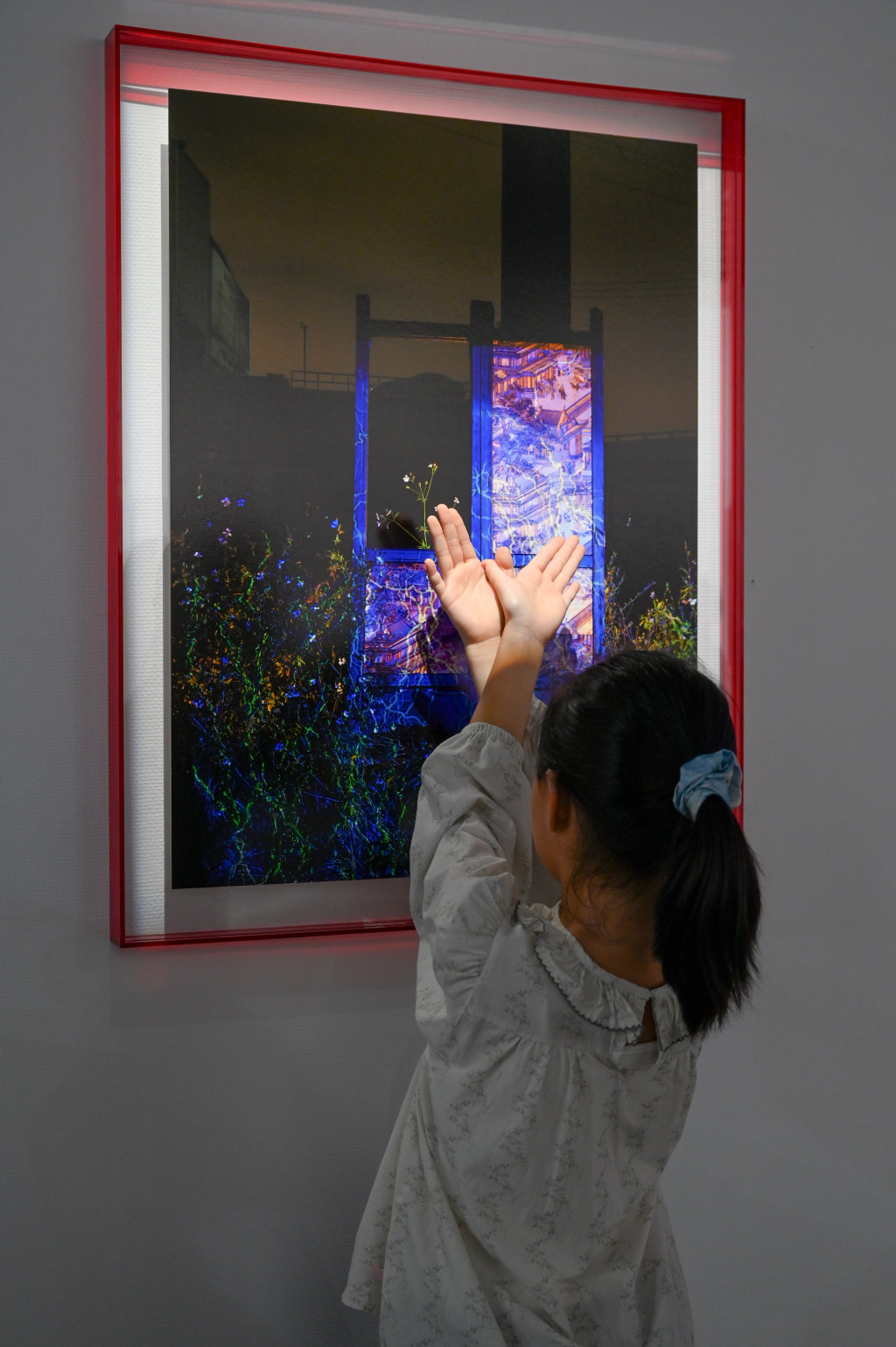 “瑞土境安：浙江瑞安摄影联展”的一件作品前，小女孩正在比划手势和作品互动。澎湃新闻记者 吴栋 图