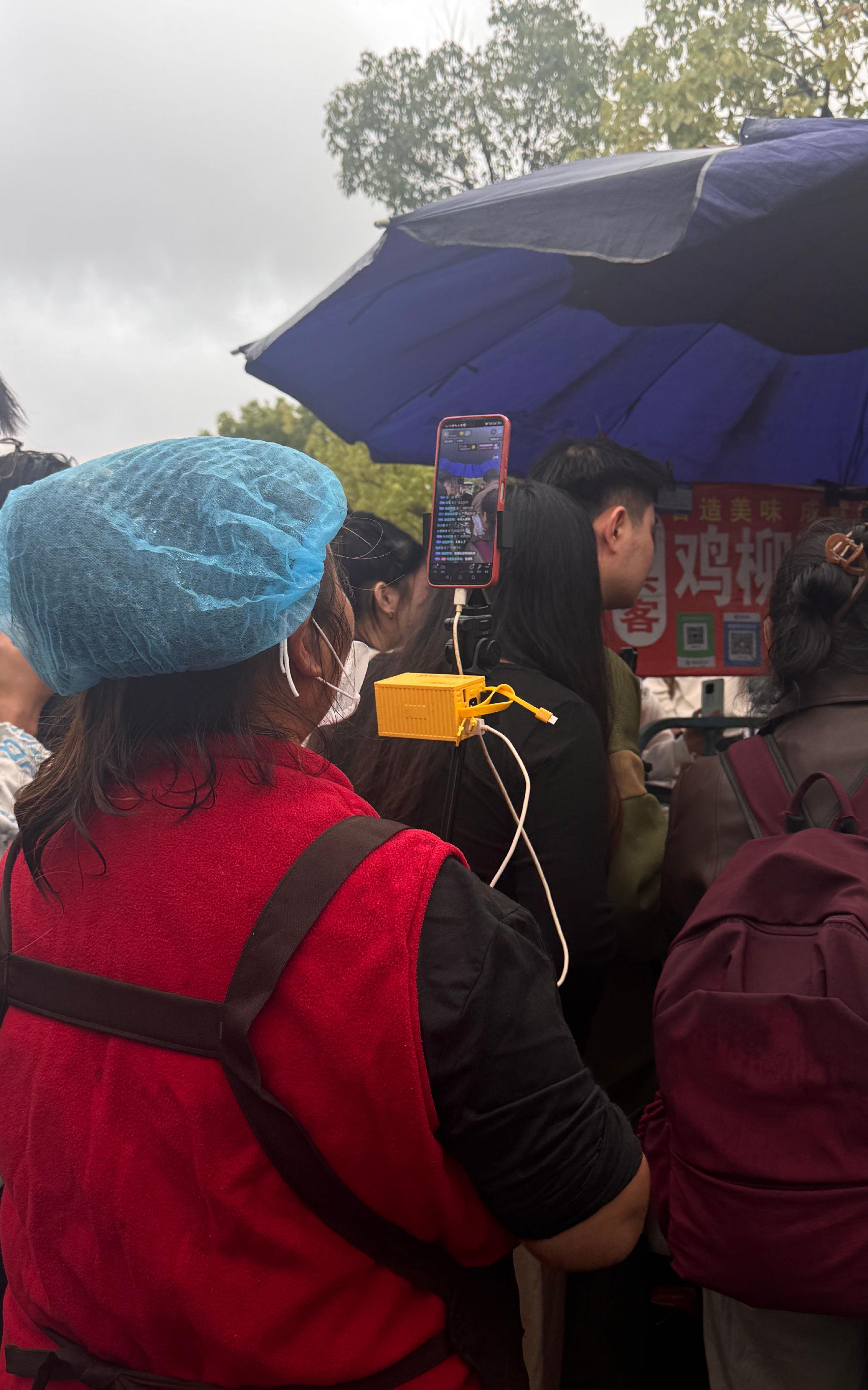 10月21日，隔壁賣手抓餅的大姐在直播雞排哥。 新京報記者 熊麗欣 攝