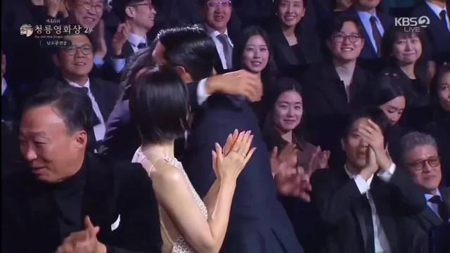 旁边的大叔好像要提醒他等等，夫妻俩拥抱呢